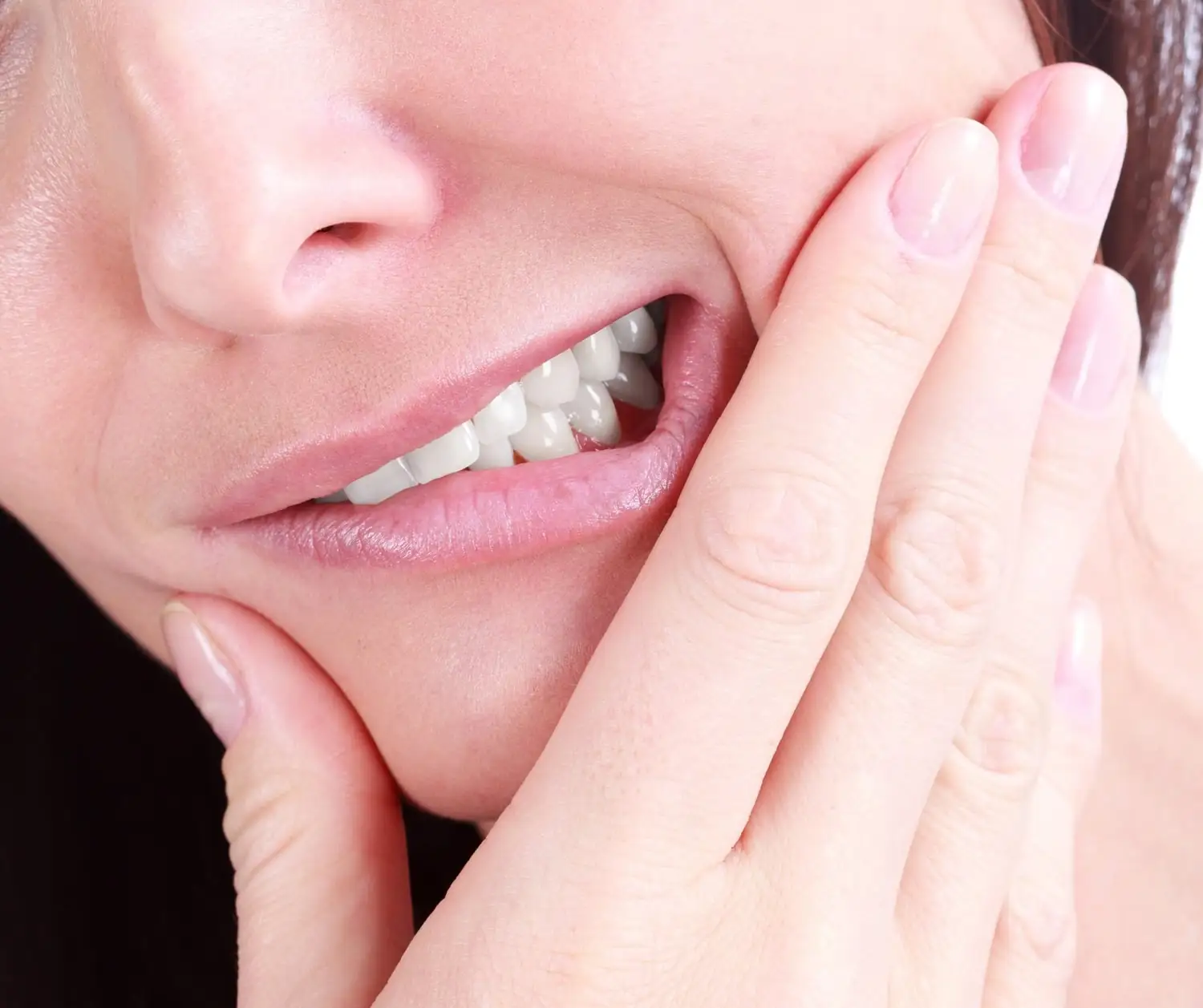 A person holding their jaw and cheek with a grimace, exposing clenched teeth.